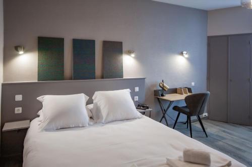 a bedroom with a large white bed with a table at lhotel in Thouars