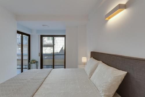 um quarto branco com uma cama grande e janelas em La Playa - Alicante City Center em Alicante