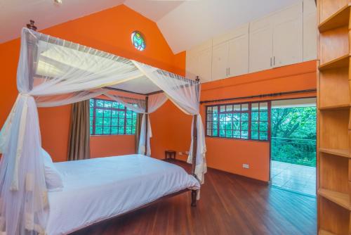 Twiga Hill Garden 5 في نيروبي: غرفة نوم بجدران برتقالية وسرير بمظلة