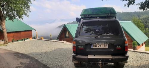 a black truck parked in front of a cabin at Etno selo ŽURIĆ in Mojkovac