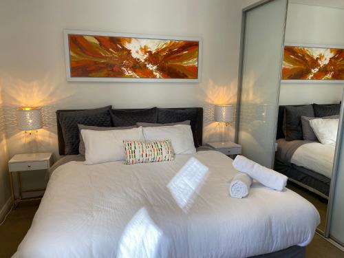 a bedroom with a large white bed with two lamps at Governor Luxe 1 BR Apartment in the heart of Barton WiFi Gym Wine Secure Parking Canberra in Kingston 
