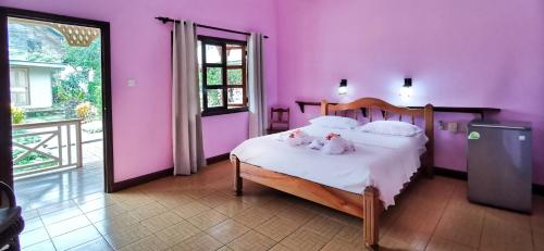 a bedroom with pink walls and a bed with stuffed animals on it at Bernique Guesthouse in La Digue