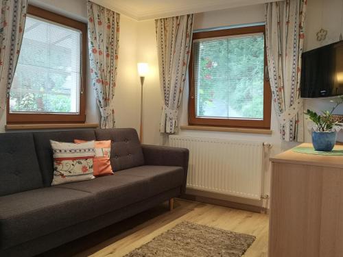 a living room with a couch and two windows at Neurauthof in Zellberg