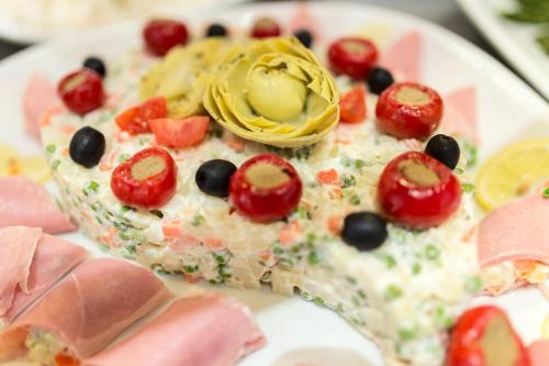 a slice of pizza with tomatoes and olives on a plate at Bibione Palace Hotel in Bibione
