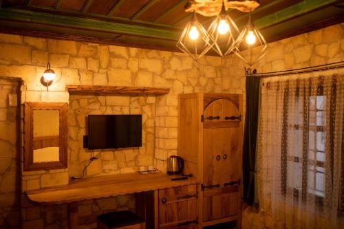 a room with a tv on a stone wall at Pome Granate Cave Hotel in Nevşehir