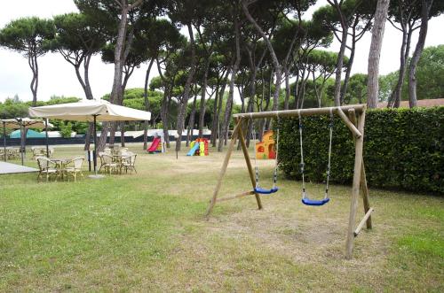 een schommel in een park met stoelen en een parasol bij Casa per ferie Il Pioppo in Marina di Massa