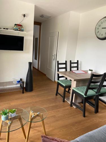 a living room with a table and chairs and a clock at Landhaus Zirben in Bad Kleinkirchheim