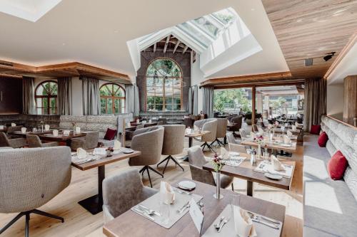 ein Restaurant mit Tischen, Stühlen und Fenstern in der Unterkunft Hotel Elisabeth, 4 Sterne Superior in Kirchberg in Tirol