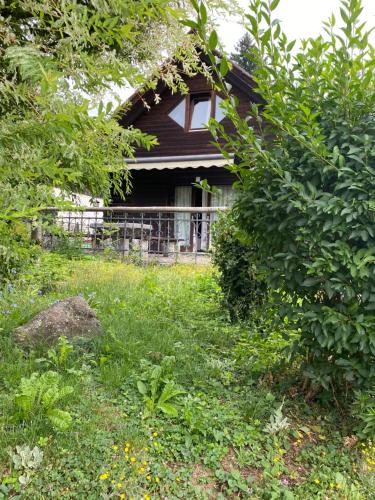 a house obscured by trees and a field of grass at Alice Chalet Bled - Adults only in Bled
