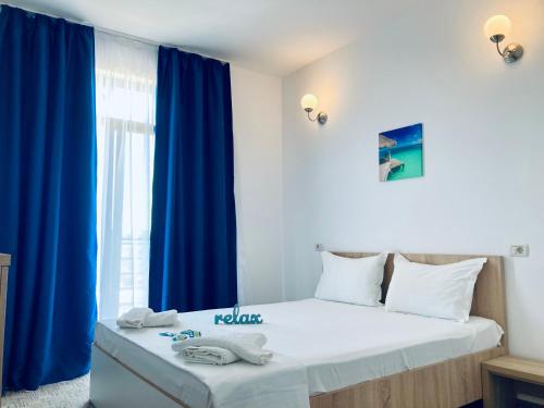 a bedroom with a large bed with blue curtains at RIMA Del Mar in Eforie Nord
