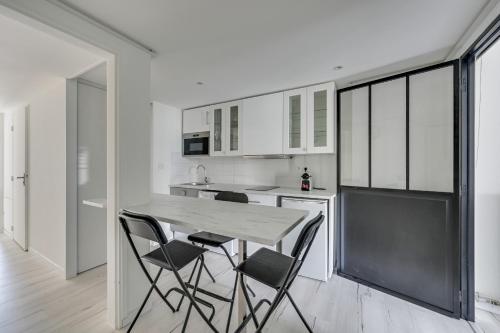 a white kitchen with a table and chairs at DIFY Splendide - Jean Mace in Lyon