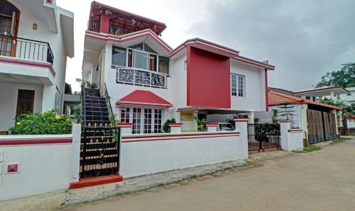 a red and white house with a gate at Treebo Avyukta Stay in Madikeri