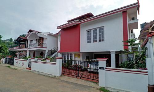a red and white house with a black fence at Treebo Trend Avyukta Stay in Madikeri