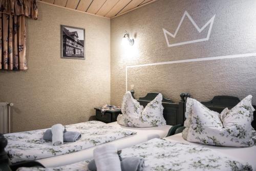 two twin beds in a room with a crown on the wall at Pension Zur Krone in Martinfeld