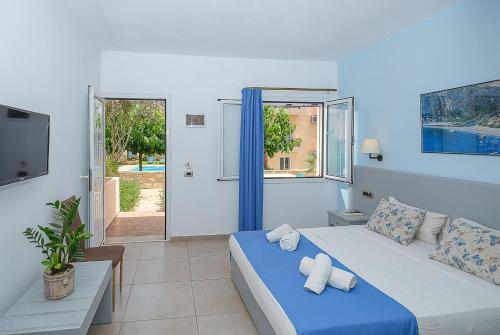 een slaapkamer met een blauw bed en een televisie bij Calypso Hotel in Matala