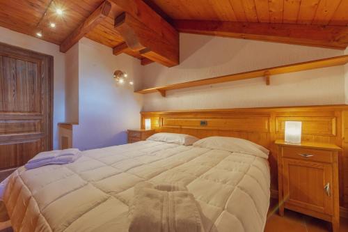 - une chambre avec un grand lit dans une pièce dotée de plafonds en bois dans l'établissement Chalet Pontal 5, à Courmayeur
