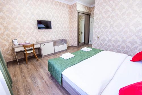 a bedroom with two beds and a desk with a television at Damla Hotel Baku in Baku