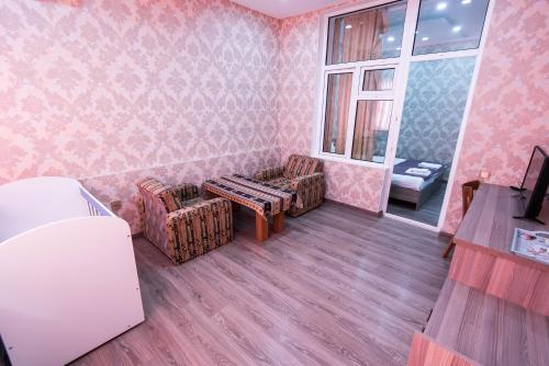 a room with pink wallpaper and two chairs and a table at Damla Hotel Baku in Baku
