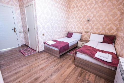 two beds in a room with wooden floors and walls at Damla Hotel Baku in Baku