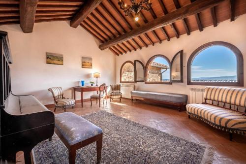 uma sala de estar com um sofá, cadeiras e janelas em Villa La Corte Di Campalli em Castellina in Chianti