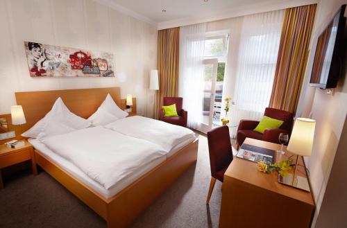 Cette chambre comprend un lit, un bureau et des chaises. dans l'établissement Hotel Noltmann-Peters, à Bad Rothenfelde