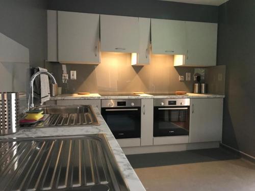 a kitchen with white cabinets and a stove top oven at Rostrevor Mountain Lodge "Cosy & Friendly" in Rostrevor