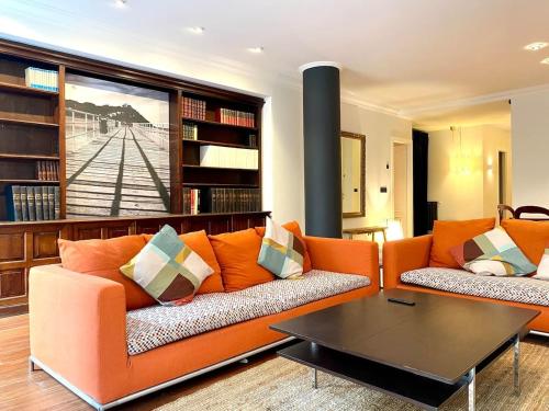 uma sala de estar com um sofá laranja e uma mesa em Luxury stay in the heart of the city em San Sebastián