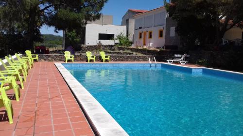 a swimming pool with yellow chairs next to a building at Quinta Das Lameirinhas in Marvão