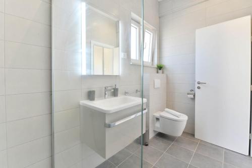 biała łazienka z umywalką i toaletą w obiekcie Villa Manuela with heated pool 400 meters from the sea - by TA Leut Agency w mieście Vrsi