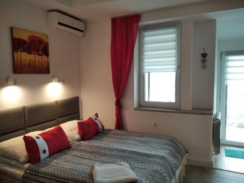 a bedroom with a bed with red and white pillows at Zielone Wzgórze na Starówce in Sandomierz