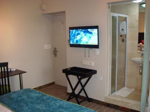 a room with a television on a wall with a sink at Signal Hill Lodge in Cape Town