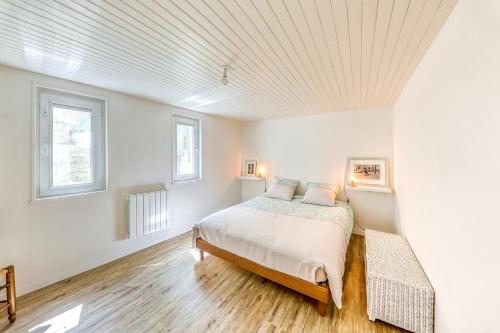 a white bedroom with a bed and two windows at El Nido in Morlaix