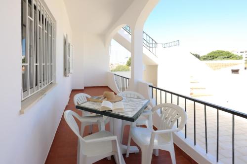 uma varanda com uma mesa e cadeiras brancas e uma janela em Apartamentos Pedro for Families by Bedzy em Albufeira