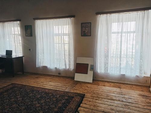 an empty living room with white curtains and a television at Khachats Toun Heritage in Meghri
