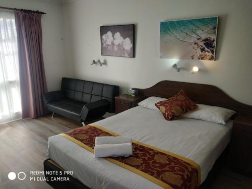 a hotel room with a bed and a chair at Australia Park Motel in Albury