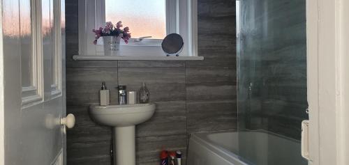 a bathroom with a sink and a toilet and a window at The Beverley Suite in Sheringham