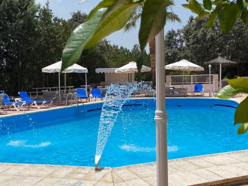 una fuente en una piscina con sillas y sombrillas en Hotel Don Juan, en Navalvillar de Pela