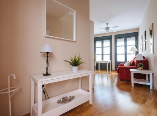 ein Wohnzimmer mit einem weißen Tisch und einem roten Sofa in der Unterkunft Torneo Suite Apartment in Sevilla