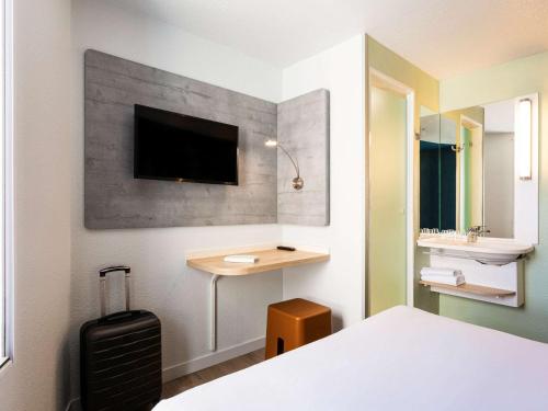 - une chambre avec un lit et un bureau avec une télévision murale dans l'établissement ibis budget Bordeaux Centre - Gare Saint Jean, à Bordeaux