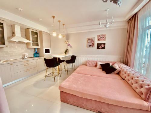 a living room with a pink couch and a kitchen at DeLight Apartments in Boryspilʼ