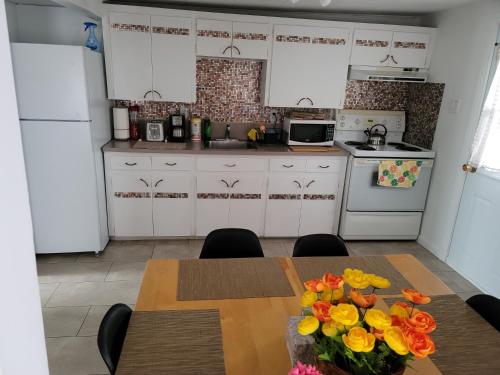 a kitchen with white cabinets and a table with flowers on it at Vibrant apartment in the heart of the town in Edmundston