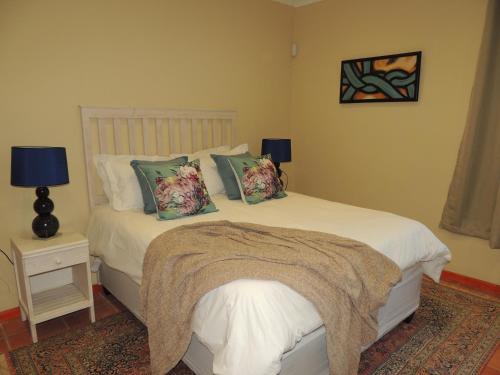een slaapkamer met een wit bed met kussens erop bij Stone Haven at Nieu Bethesda in Nieu-Bethesda