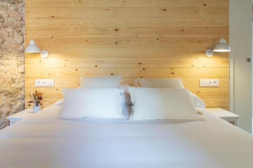 ein Schlafzimmer mit einem weißen Bett und einer Holzwand in der Unterkunft Bruma Boutique Apartment in Girona
