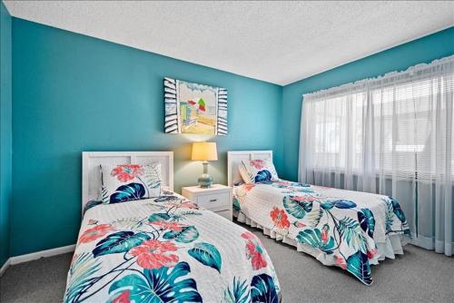 twee bedden in een kamer met blauwe muren bij Sea Oats 241 Apartment in Boca Grande
