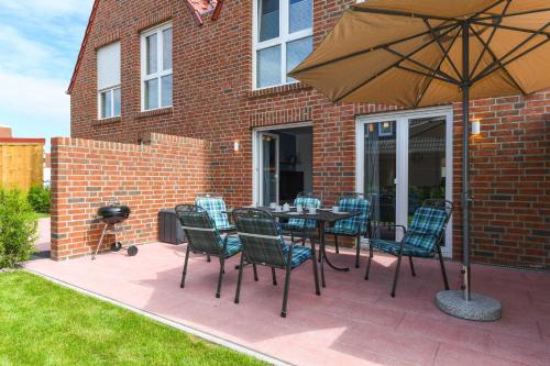 eine Terrasse mit einem Tisch, Stühlen und einem Sonnenschirm in der Unterkunft Ferienhaus Ella in Dornumersiel