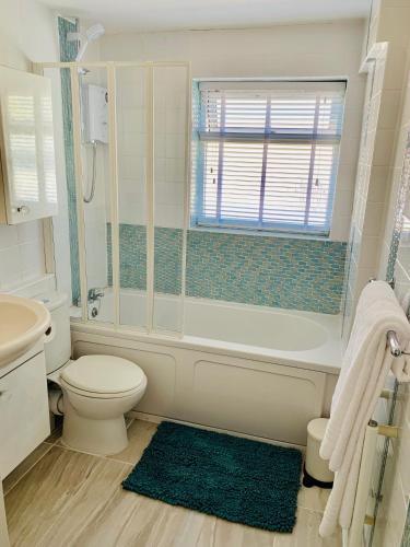 a bathroom with a toilet and a tub and a sink at Lovely home from home apartment 8 mins walk to beach with free parking and sun deck 2 bed sleeps 4 in Lyme Regis