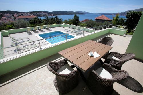 a wooden table and chairs on a balcony with a pool at Apartments Delta in Trogir