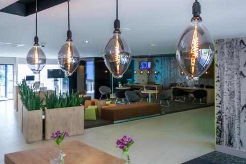 a lobby with tables and chairs and lights at Novotel Rotterdam - Schiedam in Schiedam