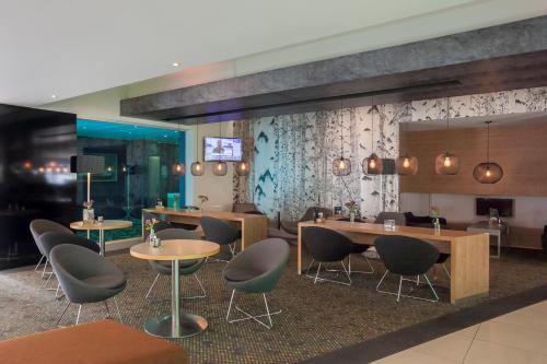 a restaurant with tables and chairs and a wall at Novotel Rotterdam - Schiedam in Schiedam