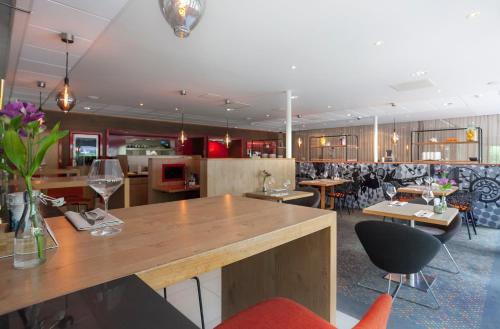 a restaurant with a bar with chairs and tables at Novotel Rotterdam - Schiedam in Schiedam